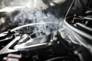 Motor de un coche sobrecalentado con vapor y medidor de temperatura